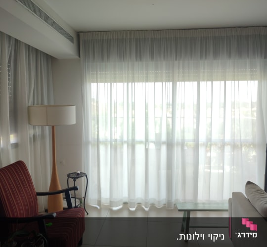 וילון לבן שקוף תלוי על חלון גדול בסלון